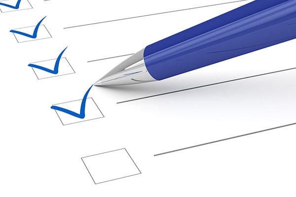image of a pen checking off boxes on paper